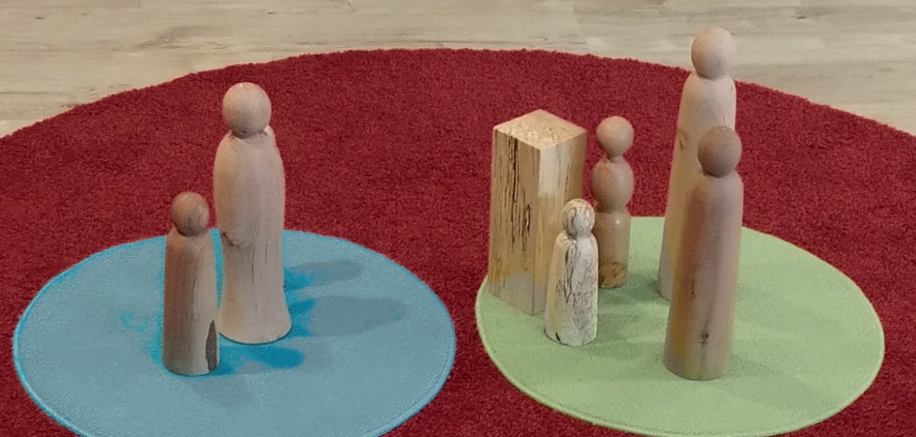 Holzfiguren in zwei Gruppen auf runden Matten